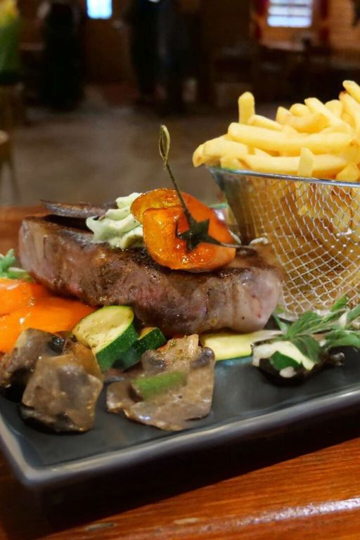 Saftiges Steak mit Kräuterbutter auf gebratenem Gemüse