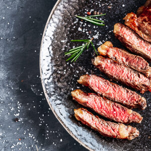 Grilled sliced beef steak with rosemary top view